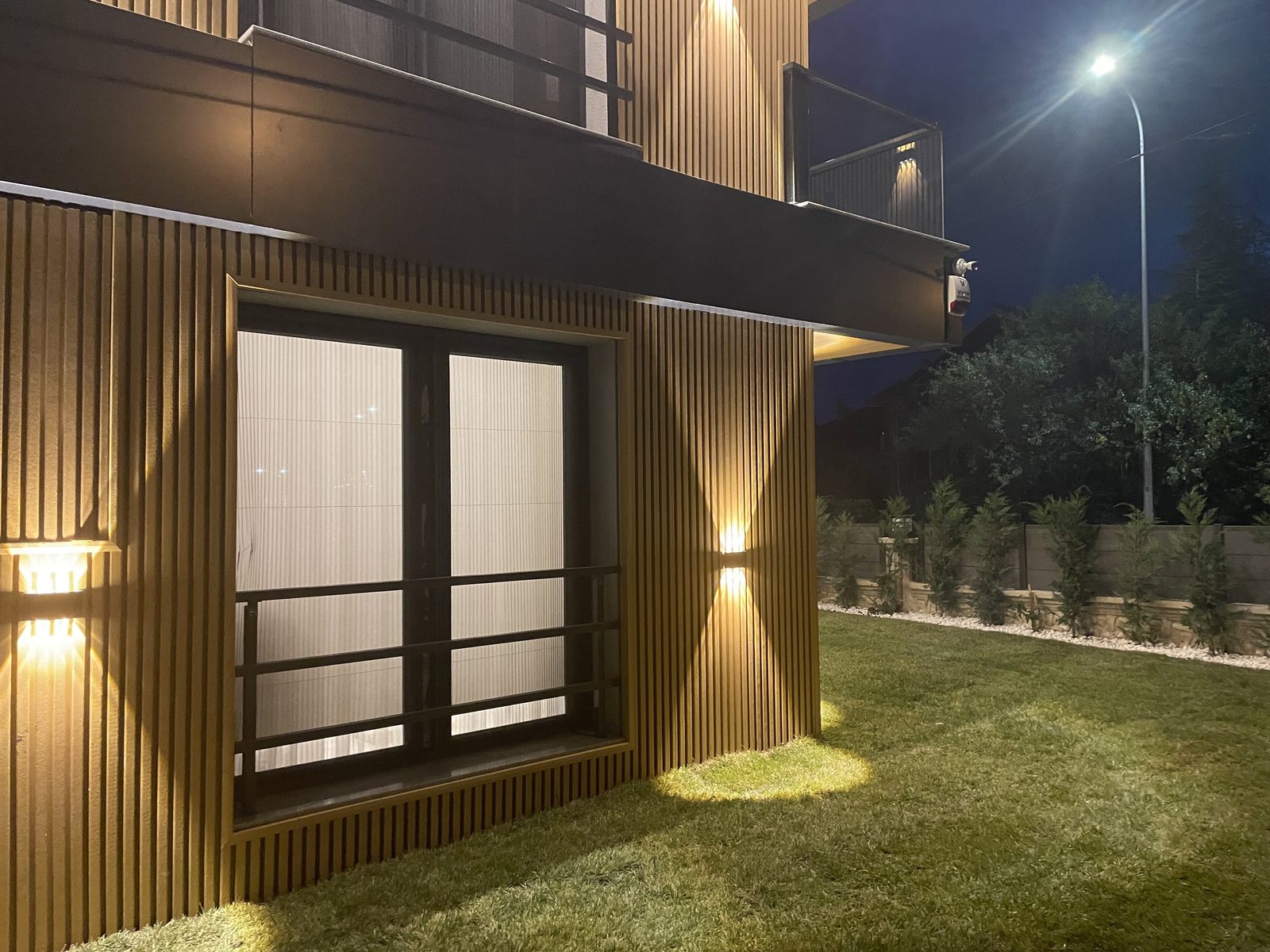 Villa clad in composite wall cladding, with night lighting